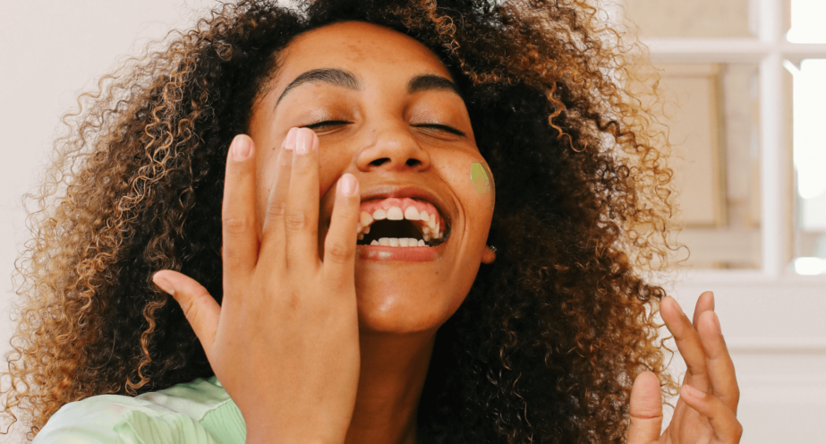 mulher negra sorrindo passando um cosmético